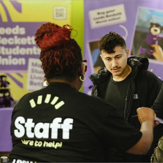 An LBSU staff member speaking to a student at a fair stand